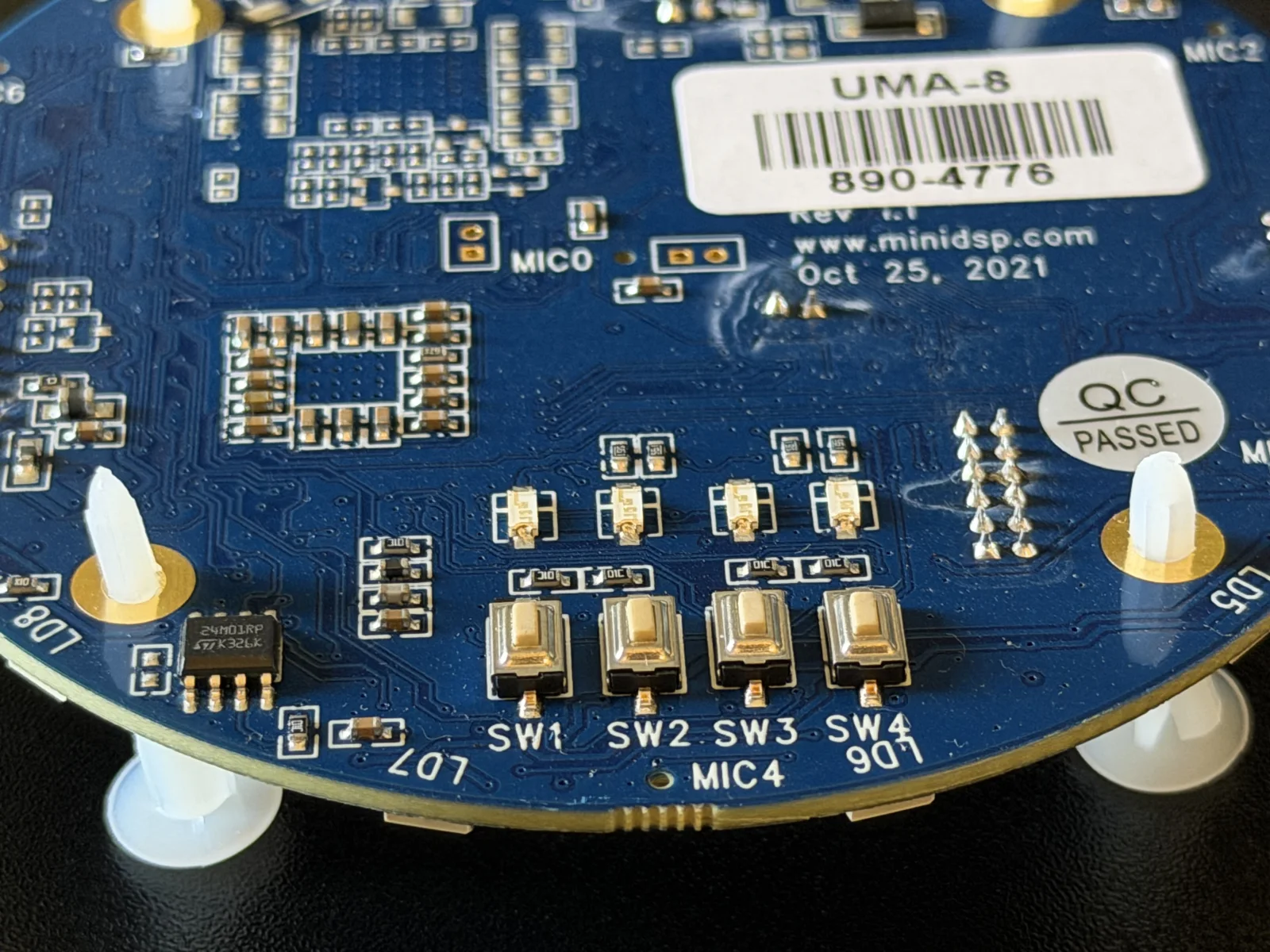 Close-up of the miniDSP UMA-8 circuit board showing the six MEMS microphone capsules arranged on a ring around a seventh centre capsule, with a ruler for scale
